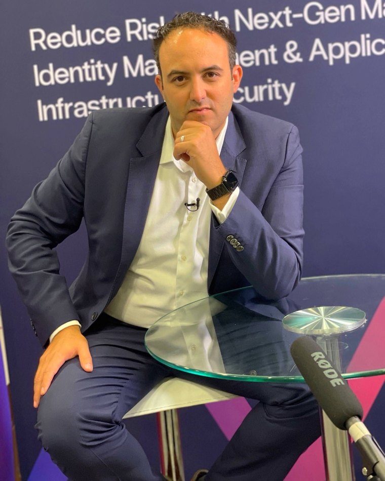 Alon Nachmany speaking at an event, seated with a microphone in front of a presentation slide.